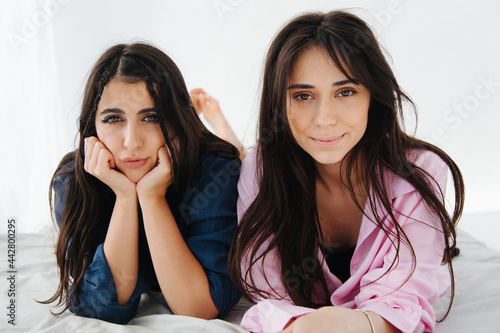 smiling armenian women looking at camera near bored friend photo