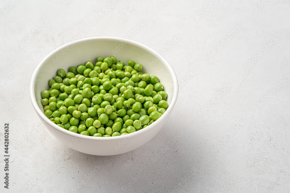 Open peas with a white bowl on a gray background. Open peas with a white bowl on a gray background.