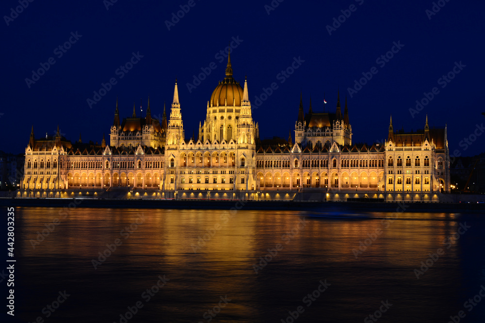 Panoramic view of Hungarian Parliament reflecting in Danube river. Night cityscape of Budapest
