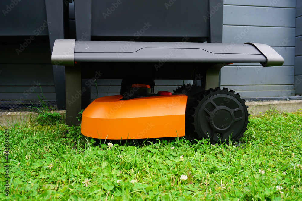 Ein Mähroboter steht auf dem Rasen unter seiner Garage Ein Mähroboter steht auf dem Rasen unter seiner Garage