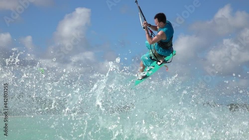 SLOW MOTION: Kitesurfer attempting a trick crashes into the spectacular turquoise ocean water while riding in windy Zanzibar. Funny shot of a male tourist failing while kiteboarding in Tanzania.