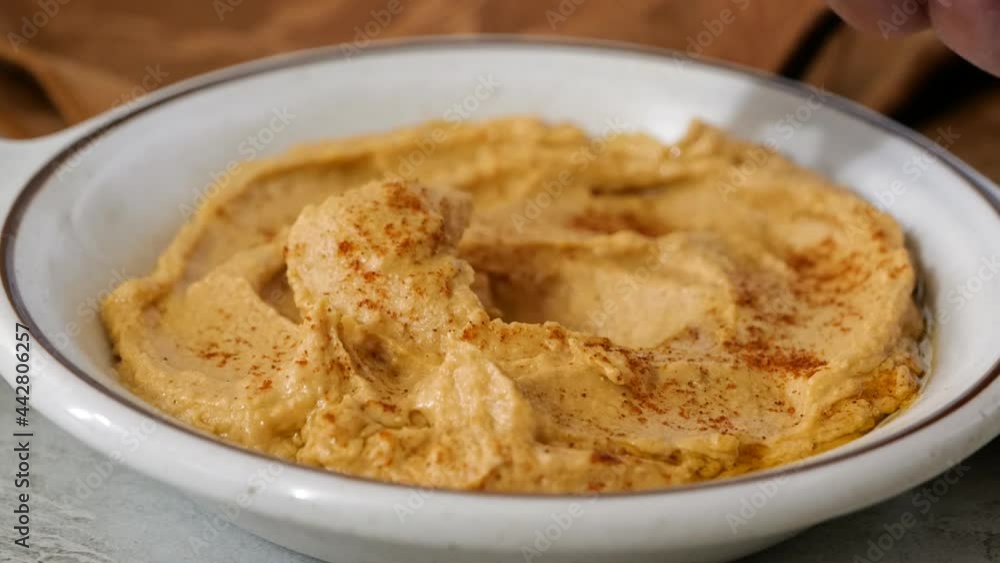 Dipping a corn tortilla chip into a bowl of hummus Dipping a corn tortilla chip into a bowl of hummus