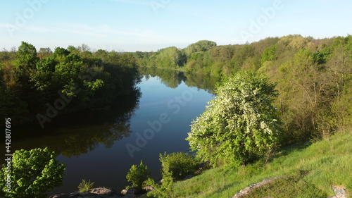 Aerial drone view flight over hill, slope. blue river, mirror reflecting surface