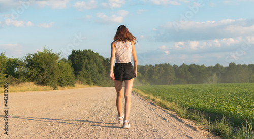 A young girl is walking along a country road