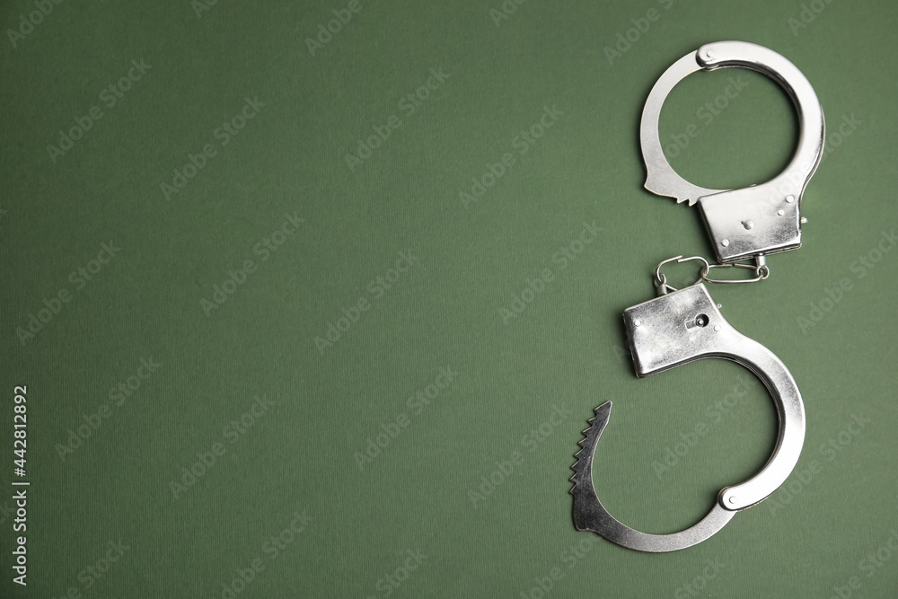 Classic chain handcuffs on dark green background, top view. Space for text Classic chain handcuffs on dark green background, top view. Space for text