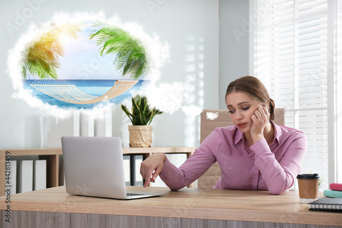 Young woman dreaming about vacation at table in office photo