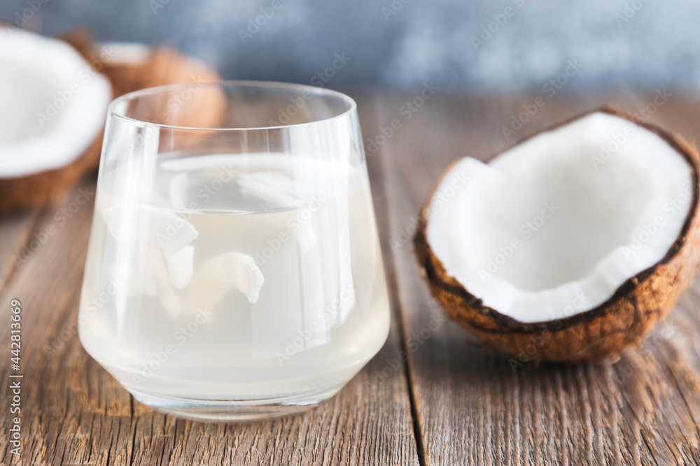 Coconut water in a glass close-up on a wooden table and a half of a fresh coconut lies nearby. Organic Coconut Detox Juice Coconut water in a glass close-up on a wooden table and a half of a fresh coconut lies nearby. Organic Coconut Detox Juice
