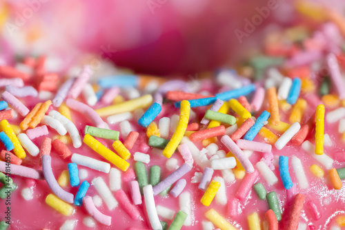 Donut Fully Close-up With Pink Icing And Colored Sprinkles. Side view.