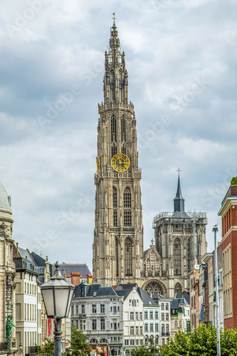 bottom view of the gothic Cathedral of Our Lady in Antwerp and the fountain against the sky on a gloomy  day and at sunset