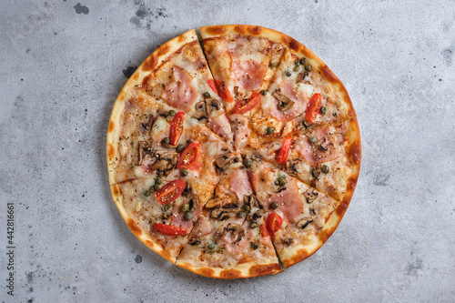 Pizza with tomatoes, ham, capers, mushrooms, mozzarella cheese, spices, sesame seeds and tomato sauce. Flat lay. On a light background