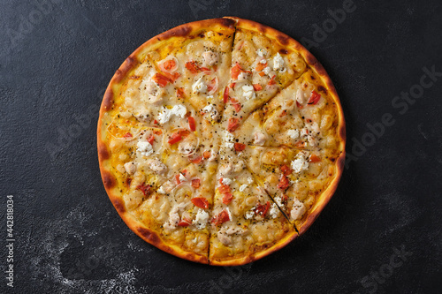 Pizza with tomatoes, chicken, onions, feta cheese, mozzarella cheese and spices. Flat lay. On a dark background.