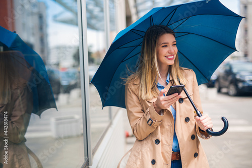 Cuadro en lienzo Happy businesswomen smiling under blue umbrella