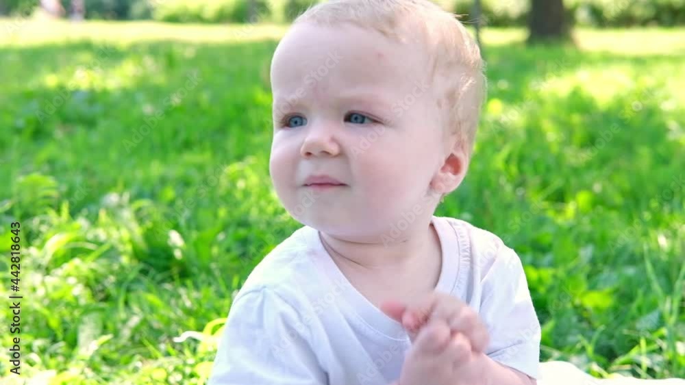 Portrait of little cute caucasian blond baby boy playing outdoors in the grass in the park. happy childhood concept