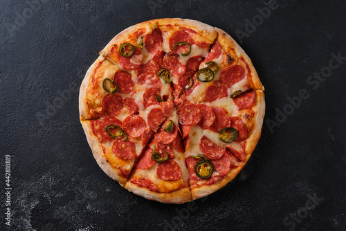 Pepperoni pizza with jalapeno peppers. A closeup of a pizza. Flat lay. On a dark background.