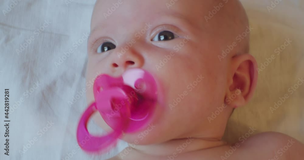 cute little newborn baby. portrait of a toddler with a pacifier in his mouth looking around with a surprised look. cute little newborn baby. portrait of a toddler with a pacifier in his mouth looking around with a surprised look.