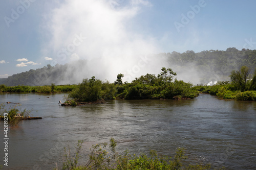 The white mist and water splash created by the Iguazu falls in Garganta del Diablo, in Misiones, Argentina. The river flowing across the forest vegetation. photo