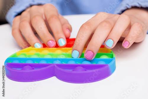 
Little girl hands with beautiful manicure nails holding toy, pop it
