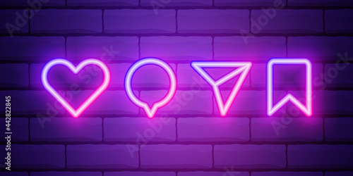 Heart icon with repost and comment neon signs icons on a dark brick wall background.