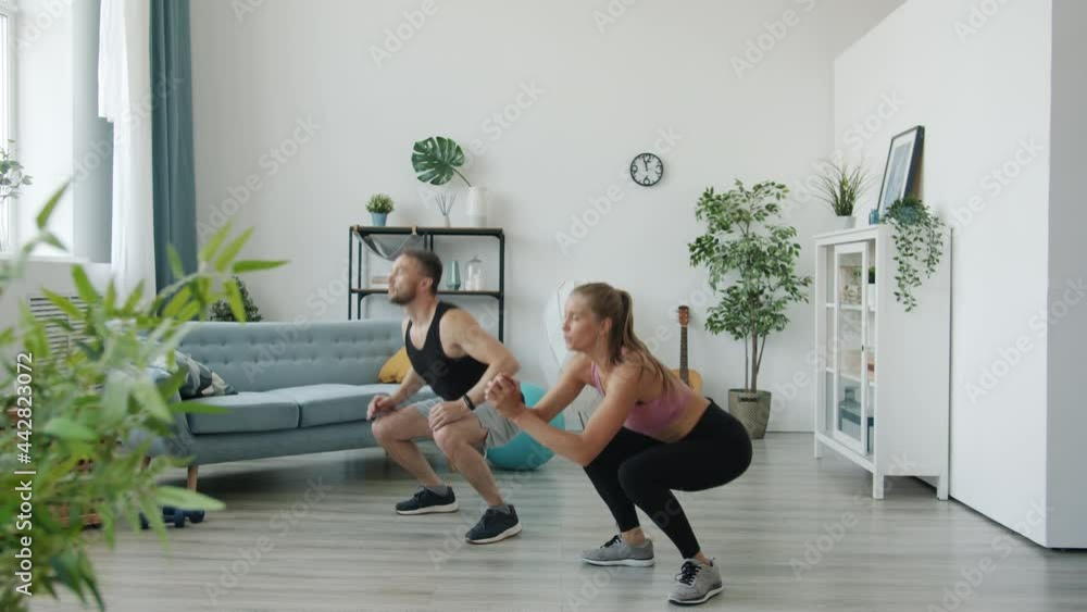 Man and woman are doing high intensity interval training exercising together at home. Young people are wearing stylish sportswear and sneakers. Man and woman are doing high intensity interval training exercising together at home. Young people are wearing stylish sportswear and sneakers.