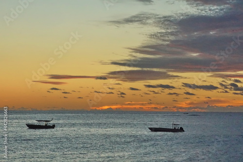 Tableau sur toile Sunset silhouetting boats in a bay in Fiji