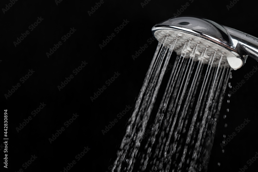 Scattering splashing water  by a shower head on a dark background