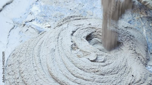 Cement mixer machine detail's dumping the fresh  mixture on the floor in an outdoor environment with daylight