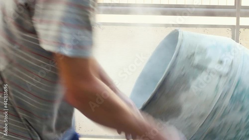 Builder worker hands empting a cement bucket on a mixxing machine