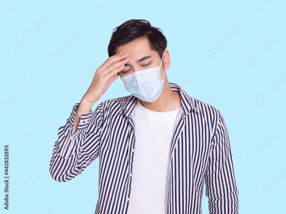 young man feel uncomfortable touching his head and wearing a protective medical mask. young man feel uncomfortable touching his head and wearing a protective medical mask.