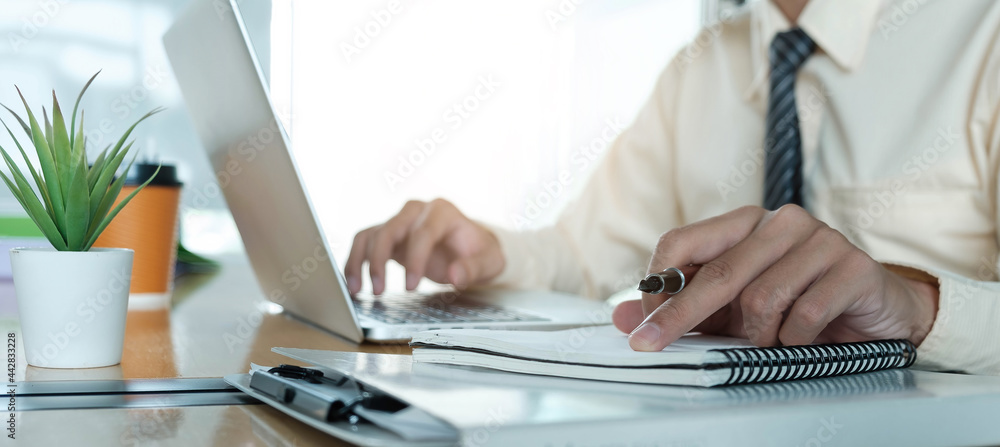 Close up Businessman using laptop for do math finance on wooden desk in office and business working background, tax, accounting, statistics and analytic research concept Close up Businessman using laptop for do math finance on wooden desk in office and business working background, tax, accounting, statistics and analytic research concept
