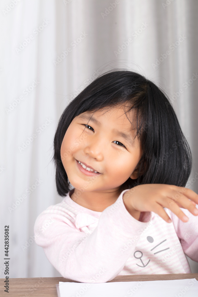 Cute Chinese girl lying on the table and smiling at the camera Cute Chinese girl lying on the table and smiling at the camera