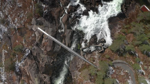 An aerial view of the Likholefossen waterfall in Gaular, Norway. Raging whitewater whirling and splashing, fed by the melting snow in the mountains. A still bridge crossing the river. photo