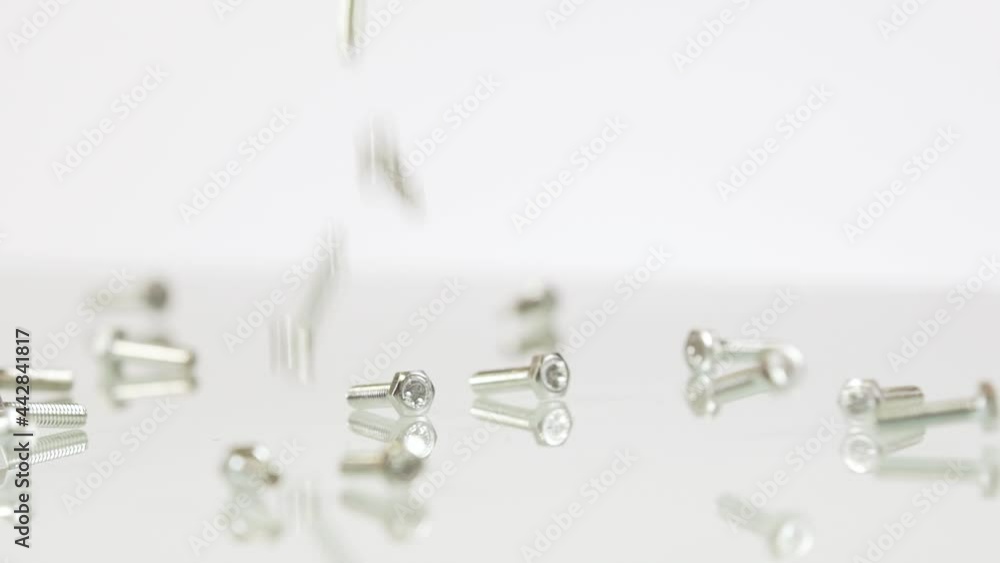 Small steel screw falling down on white background, isolated Small steel screw falling down on white background, isolated