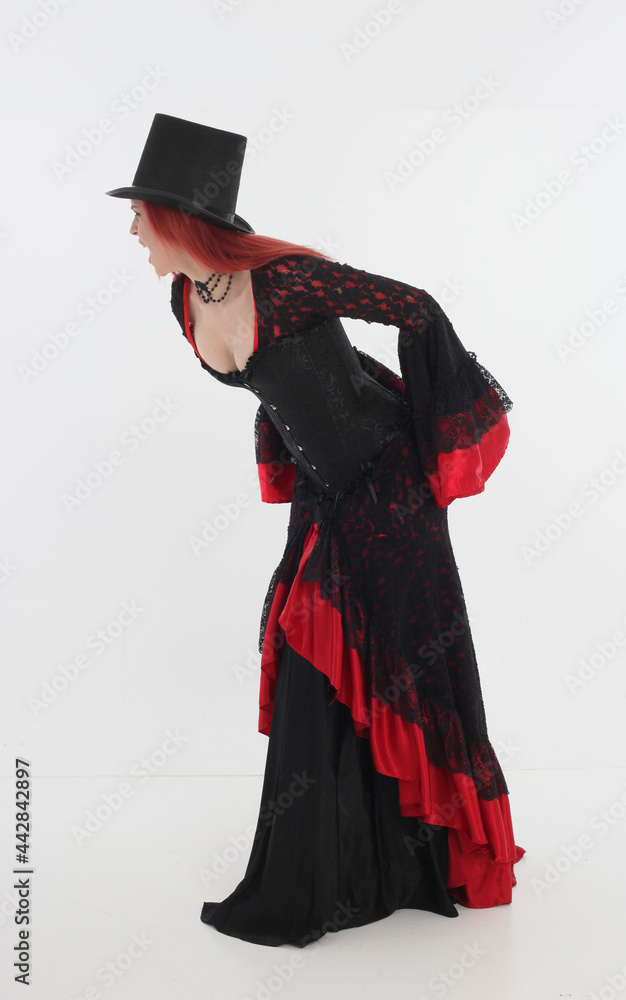 full length portrait of red haired woman wearing long black gothic vampire gown. standing pose on white studio background full length portrait of red haired woman wearing long black gothic vampire gown. standing pose on white studio background