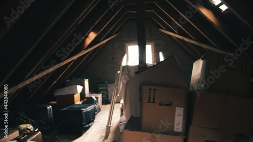 Pan Shot of an old interior vintage gable roof cluttered with boxes and cartons and the bright sun shining through the window photo