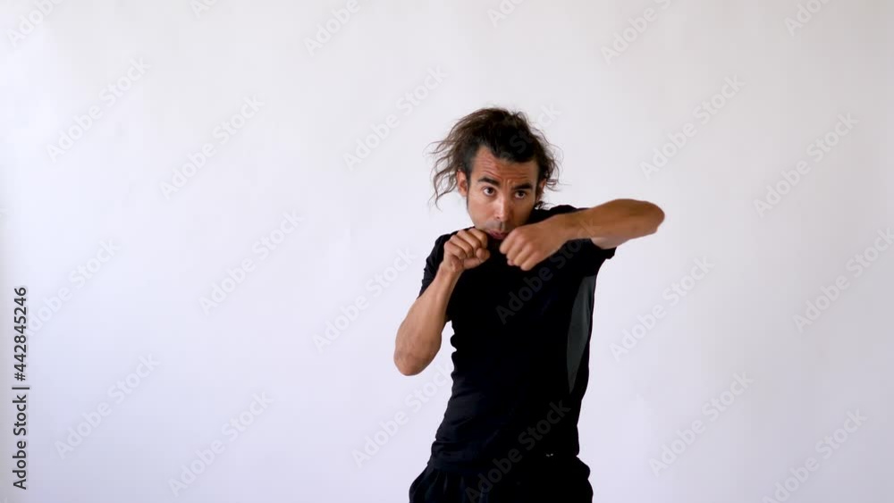 Focused Latino Man with Long Hair and Goatee Shadowboxing in White Studio Focused Latino Man with Long Hair and Goatee Shadowboxing in White Studio