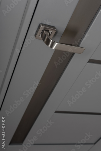 Closeup photo of chrome handle on gray door with frames