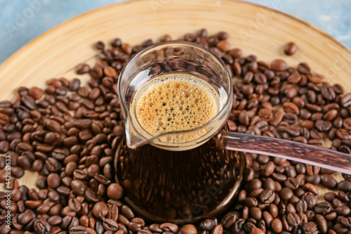 Pot with delicious turkish coffee and plate with beans on color background