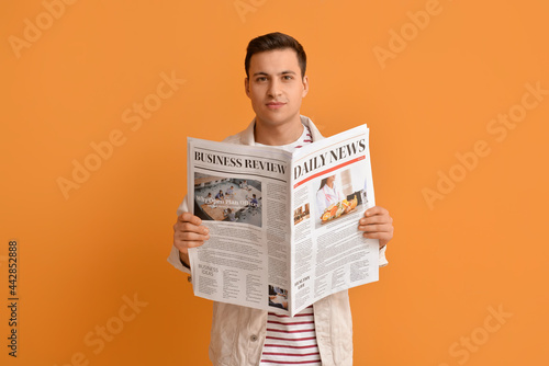 Konstfotografi Handsome young man reading newspaper on color background