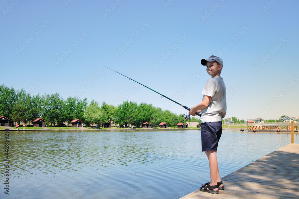 Young boy enjoys fishing at summer sunny day