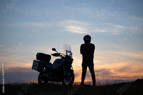 Man on his motorbike admiring sunset - summer road trip