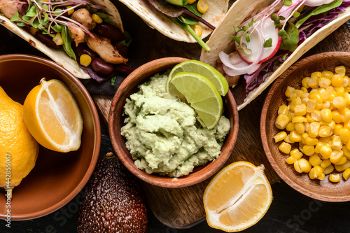 Tacos and tasty guacamole in bowl on table, closeup