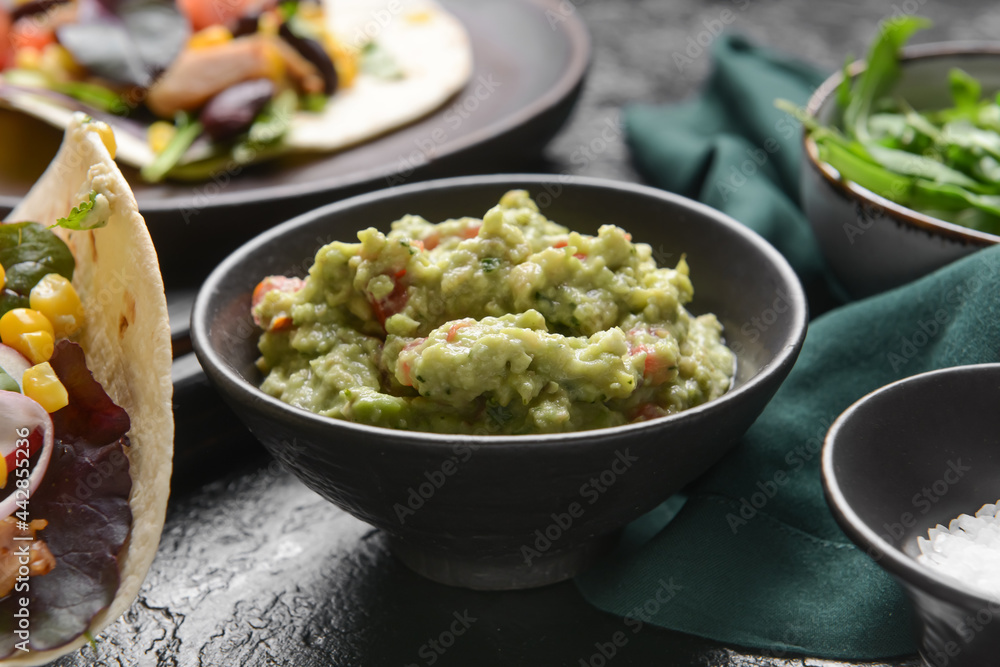 Bowl with tasty guacamole on dark background, closeup