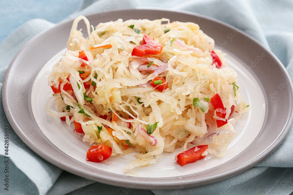 Plate with tasty sauerkraut on color background