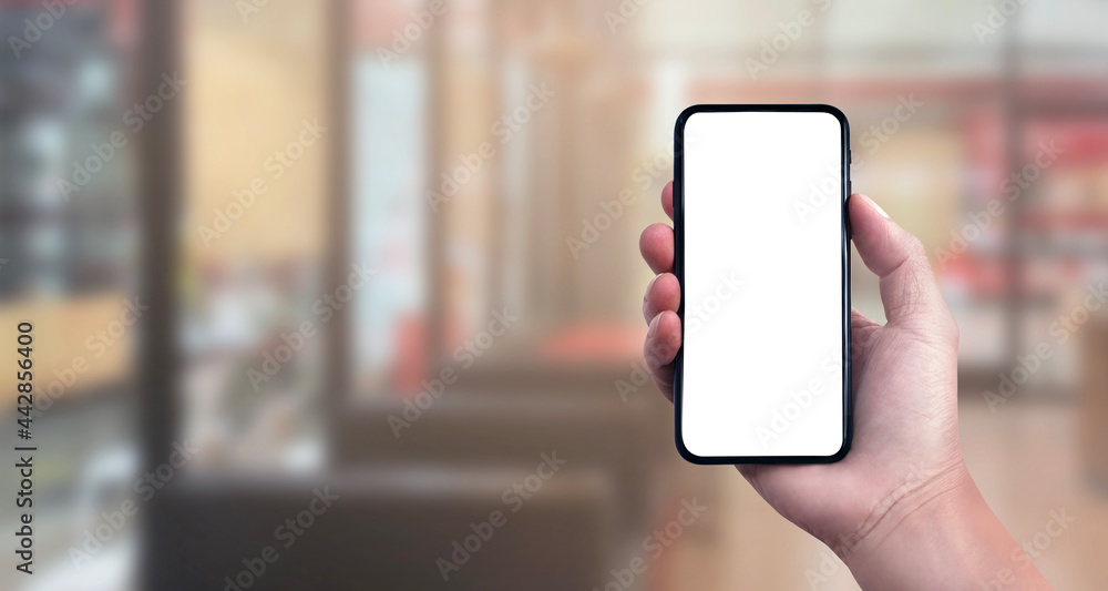 Blank screen of Mobile phone with hand holding phone on Soft blurry Supermarket store background. of free space for copy and Branding. Blank screen of Mobile phone with hand holding phone on Soft blurry Supermarket store background. of free space for copy and Branding.