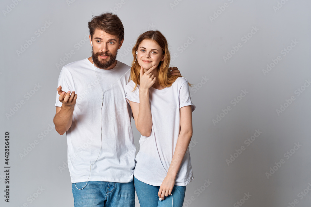 young couple in white t-shirts wearing headphones listening to music technology entertainment young couple in white t-shirts wearing headphones listening to music technology entertainment