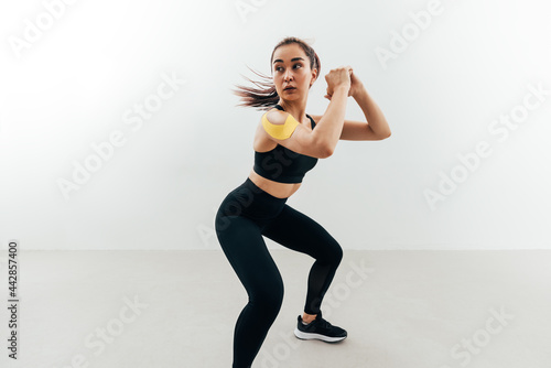 Woman with kinesiology tape on her shoulder exercising indoors. Young female doing sit ups.
