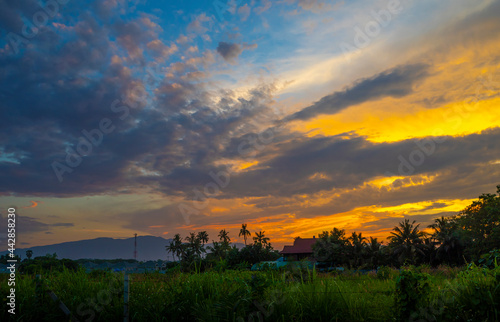 Beautiful sunset and dramatic clouds on the sky, Sunset view over the green grass field. Chiang Mai, Thailand.