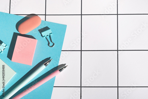 Stationery supplies on white grid paper background. Back to school concept. Top view  flat lay  copy space