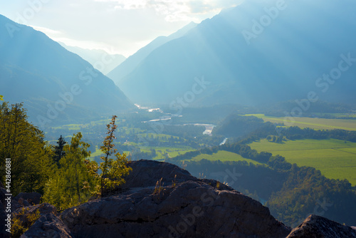 So  a river valley in Slovenian Alps. Trees on a rock. Sun rays 