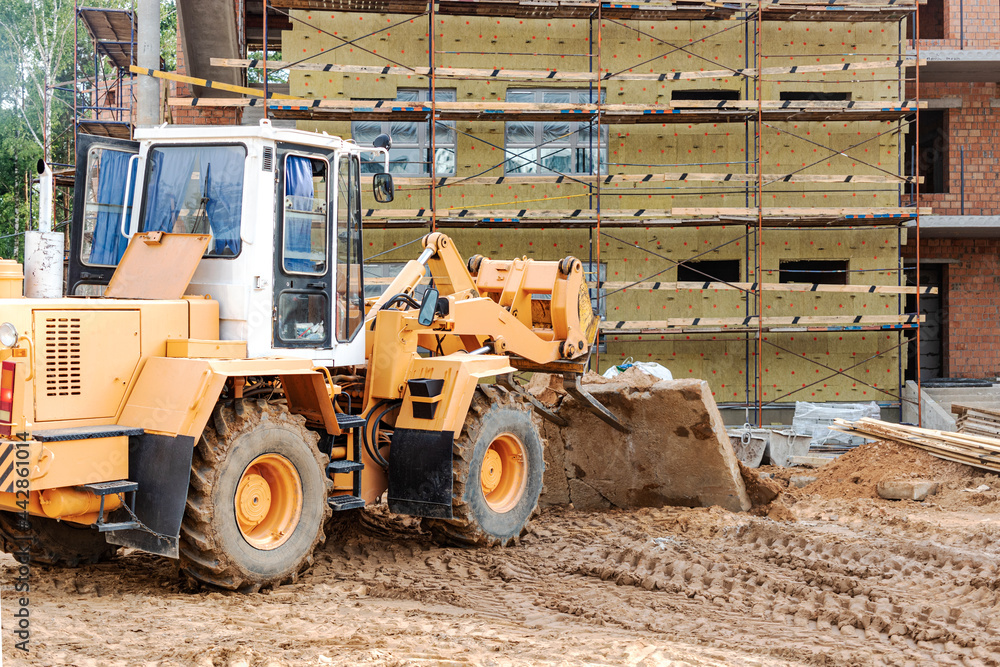 A forklift at a construction site is lifting a reinforced concrete slab. Construction machine. Industry. A forklift at a construction site is lifting a reinforced concrete slab. Construction machine. Industry.